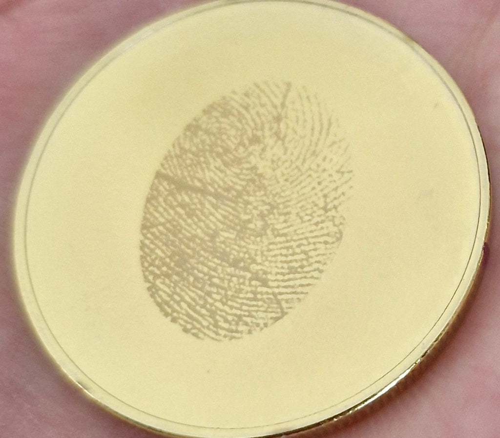 Gold coin with a fingerprint engraving held between fingers
